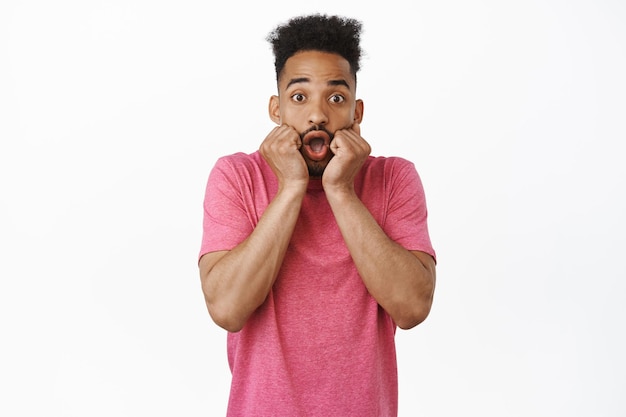 Image d'un homme afro-américain étonné et excité, haletant impressionné, regardant avec enthousiasme les grandes nouvelles impressionnantes, l'air surpris, recevoir un cadeau génial, fond blanc