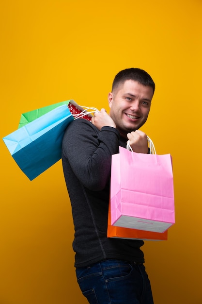 Image d'un homme brun heureux avec des sacs à provisions sur fond orange