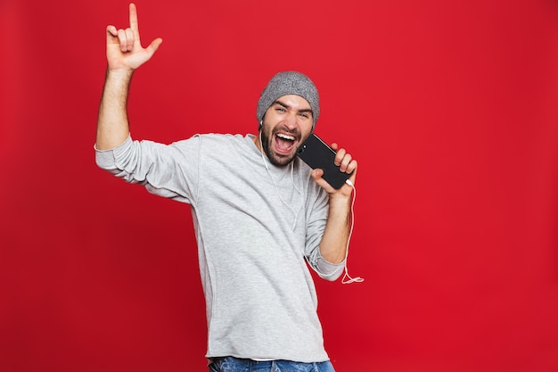 Image De L'homme Européen 30s Chantant Tout En écoutant De La Musique Avec Des écouteurs Et Un Téléphone Mobile, Isolé