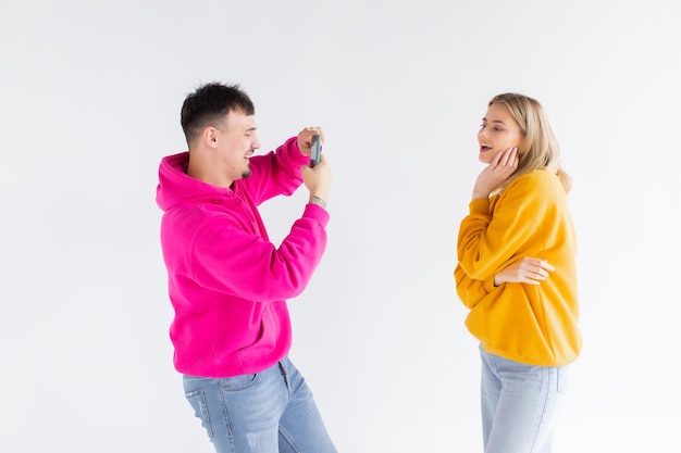 Image d'un homme prendre une photo de sa femme optimiste positive sur fond blanc par téléphone portable