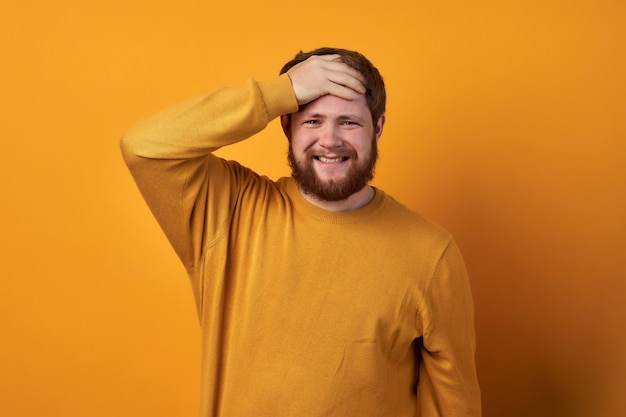 Image d'un homme en vêtements basiques, gros plan d'un beau mec malheureux avec barbe tenant les cheveux avec les mains.