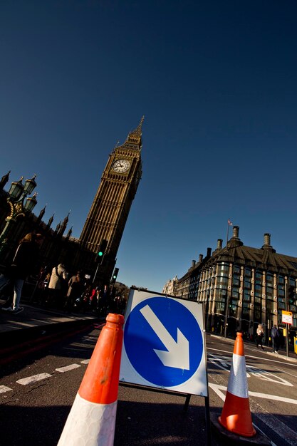 Photo image inclinée du symbole de la flèche avec des cônes de circulation sur la rue de la ville par big ben contre un ciel bleu clair