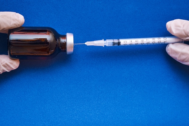 Image d'une infirmière préparant la dose de vaccin sur bleu