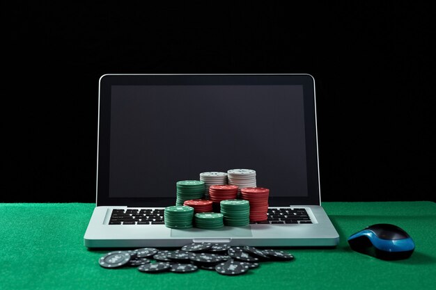 Image de jetons de casino sur un ordinateur portable à clavier à table verte. Concept de jeu en ligne, poker, casino virtuel.