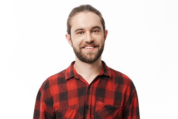 Image d'un jeune bel homme barbu souriant posant isolé sur un mur blanc.