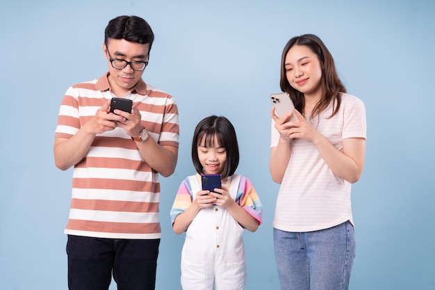 Image d'une jeune famille asiatique utilisant un smartphone sur fond bleu