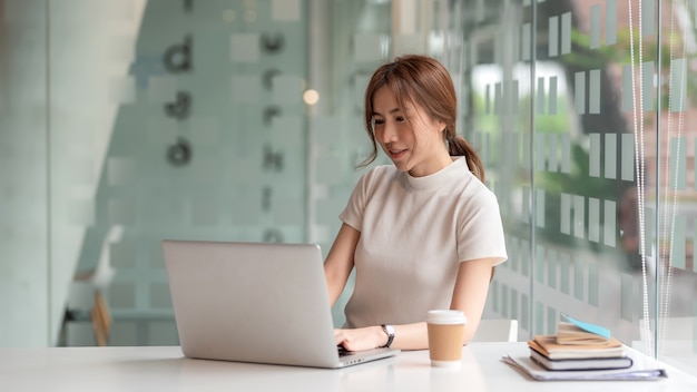 Image d'une jeune femme d'affaires asiatique travaillant au bureau à l'aide d'un ordinateur portable numérique.