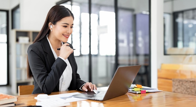 Image d'une jeune femme d'affaires joyeuse et souriante tout en travaillant avec un ordinateur portable au bureau