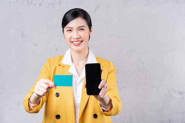 Image d'une jeune femme asiatique tenant une carte bancaire