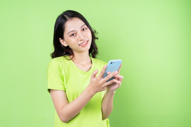 Image de jeune femme asiatique tenant un smartphone sur fond vert