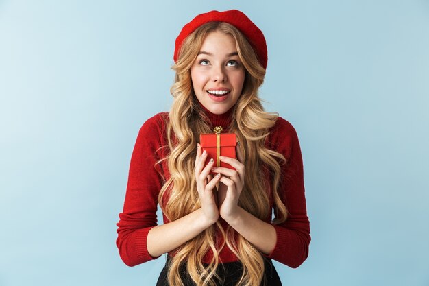 Image de la jeune femme blonde des années 20 portant un béret rouge tenant présent fort isolé