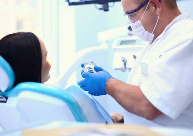 Image d'une jeune femme avec un dentiste au-dessus d'elle avant de vérifier la cavité buccale