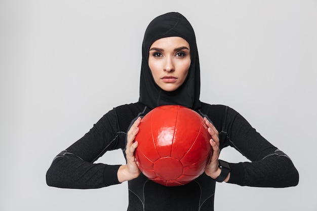 Image de jeune femme fitness musulman posant isolé faire des exercices avec ballon.