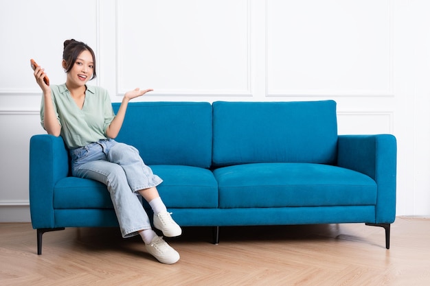 image de jeune fille asiatique assise sur un canapé à la maison