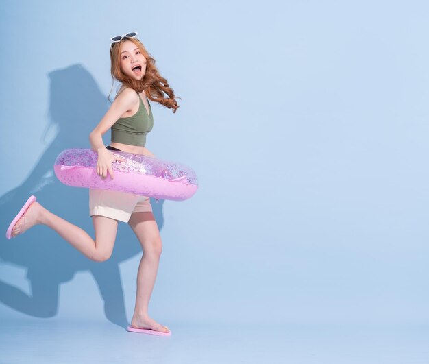 Image d'une jeune fille asiatique tenant un flotteur de natation sur fond bleu concept de vacances d'été