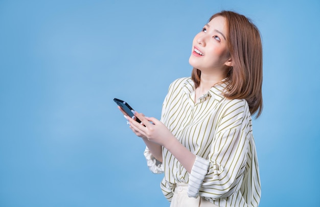 Image d'une jeune fille asiatique utilisant un smartphone sur fond bleu