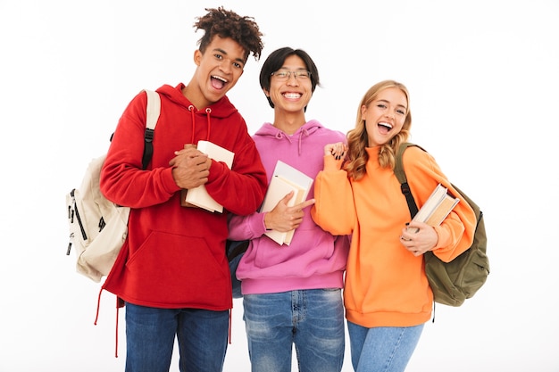 Image d'un jeune groupe d'étudiants amis heureux debout isolé, posant.