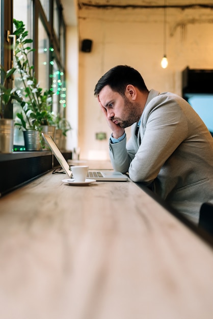 Image d&#39;un jeune homme d&#39;affaires frustré travaillant sur un ordinateur portable au café.