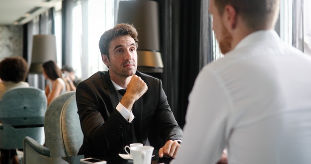 Image d'un jeune homme d'affaires avec une tasse de café communiquant avec son collègue
