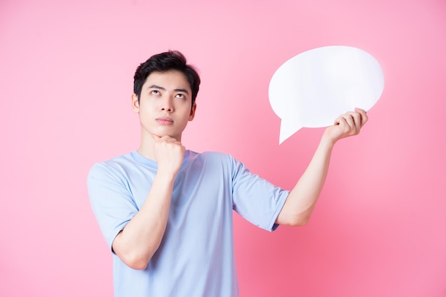 Image d'un jeune homme asiatique tenant une bulle de message sur fond rose