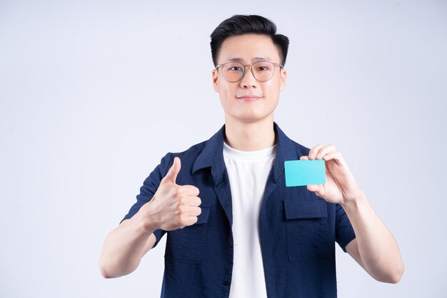 Image d'un jeune homme asiatique tenant une carte bancaire sur fond blanc