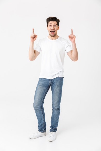 Image d'un jeune homme heureux et excité posant isolé sur un mur blanc pointant.