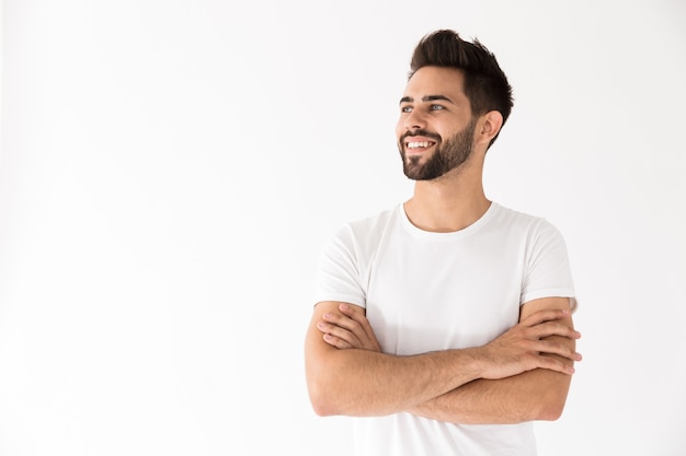 Image d'un jeune homme séduisant souriant et regardant de côté le fond isolé sur un mur blanc