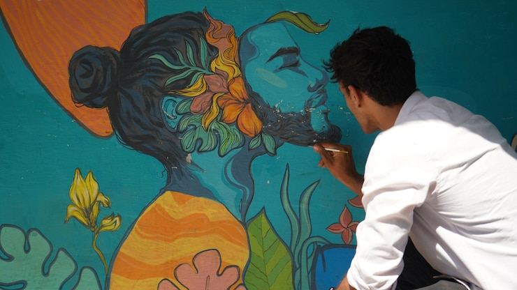 Photo image de jeune peintre ayant un pinceau et derrière une peinture