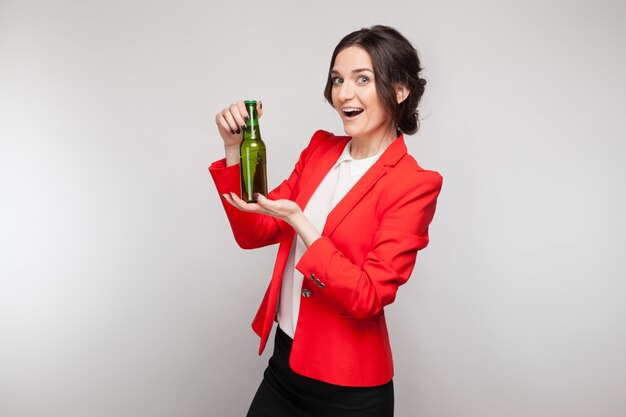 Image de jolie femme en robe rouge avec une bière verte à la main