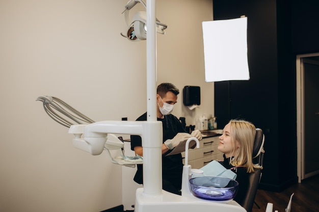 Image d'une jolie jeune femme assise dans un fauteuil dentaire au centre médical pendant qu'un médecin professionnel répare ses dents