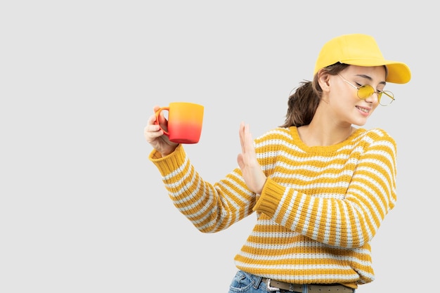 Image de jolie jeune femme dans des verres debout et tenant une tasse. photo de haute qualité