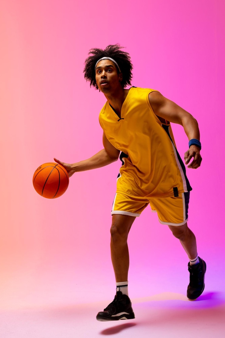 Photo image d'un joueur de basket-ball biracial faisant rebondir le basket-ball sur fond rose fluo. concept de sport et de compétition.
