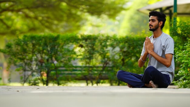 Image de la journée internationale du yoga garçon faisant namaskaara en position du lotus au parc