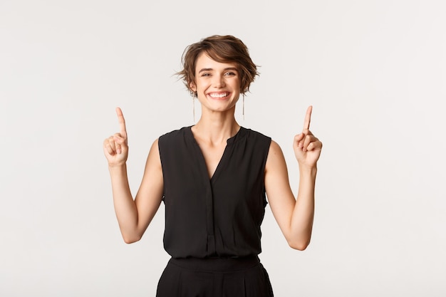 Image de joyeuse fille souriante heureuse et pointant les doigts vers le haut