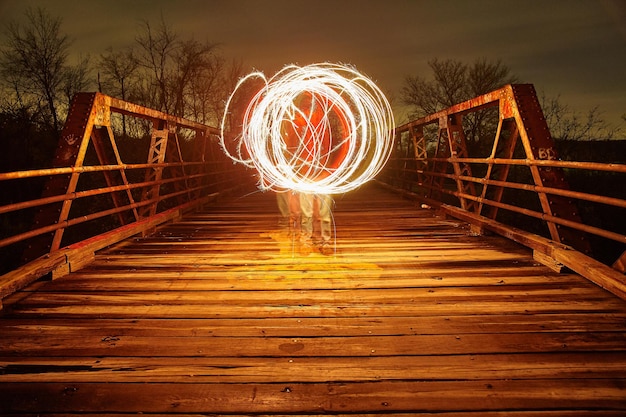 L'image d'une lumière blanche chaude illumine un pont métallique au crépuscule