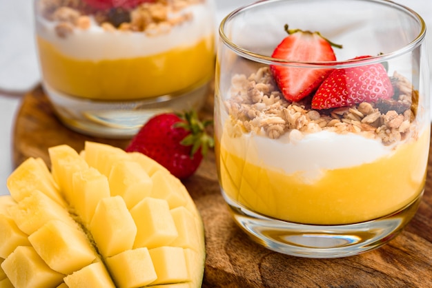 Image macro d'un verre avec un dessert de mangue, fraise, céréales et ricotta
