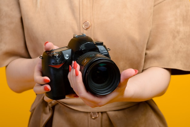 Image de mains avec appareil photo numérique sur fond jaune vide