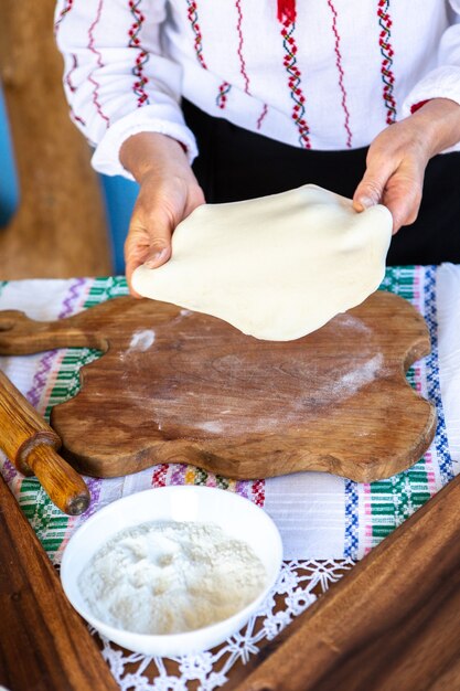 image avec les mains d'une dame cuisinant des tartes frites roumaines traditionnelles avec du fromage