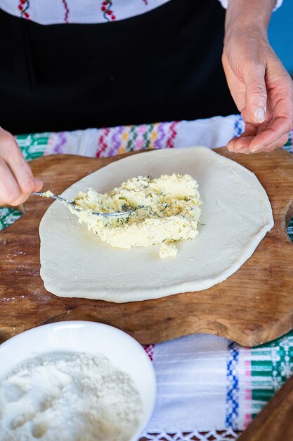 image avec les mains d'une dame cuisinant des tartes frites roumaines traditionnelles avec du fromage