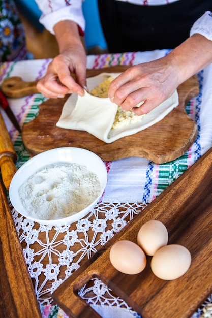 image avec les mains d'une dame cuisinant des tartes frites roumaines traditionnelles avec du fromage