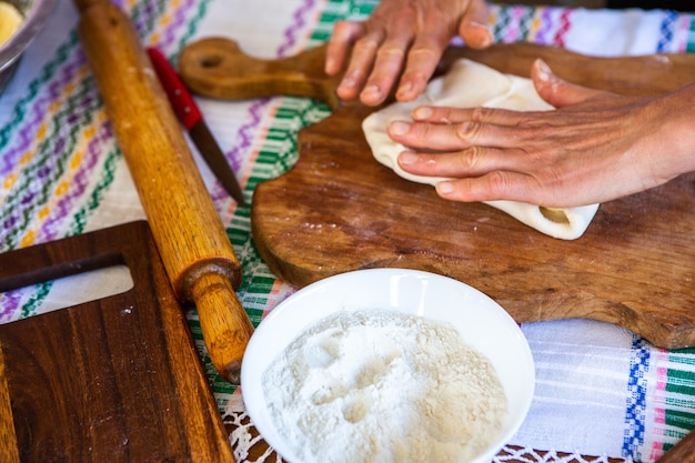 image avec les mains d'une dame cuisinant des tartes frites roumaines traditionnelles avec du fromage