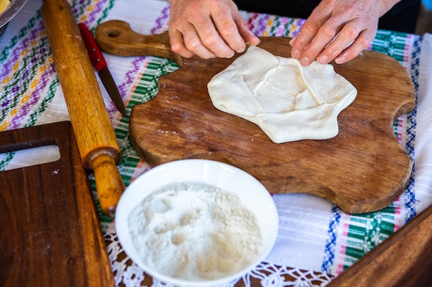 image avec les mains d'une dame cuisinant des tartes frites roumaines traditionnelles avec du fromage