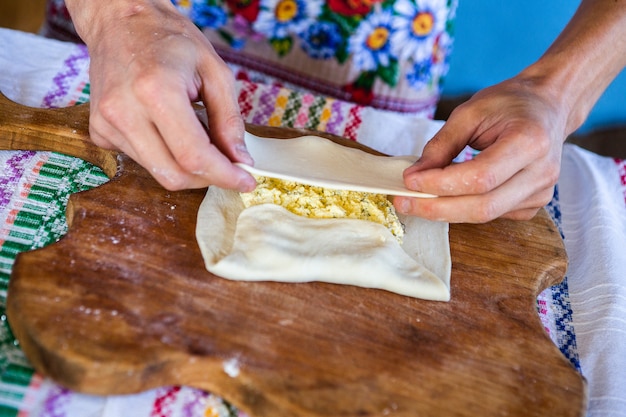 image avec les mains d'une dame cuisinant des tartes frites roumaines traditionnelles avec du fromage