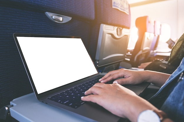 Image de maquette d'une femme à l'aide et en tapant sur un ordinateur portable avec un écran de bureau blanc vierge alors qu'il était assis dans la cabine