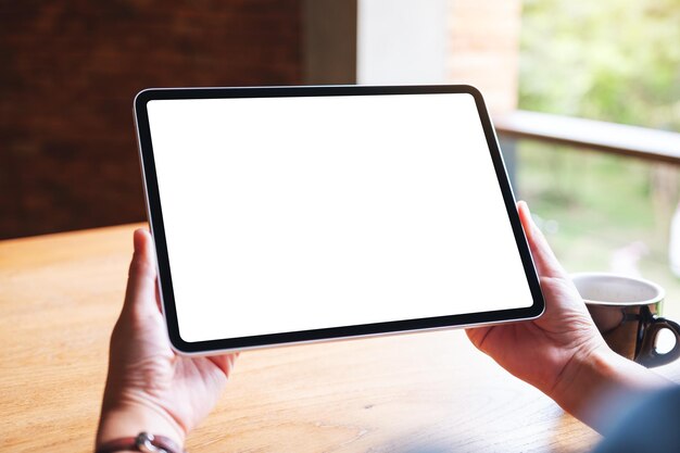 Image maquette d'une femme tenant une tablette numérique avec un écran de bureau blanc vierge au café