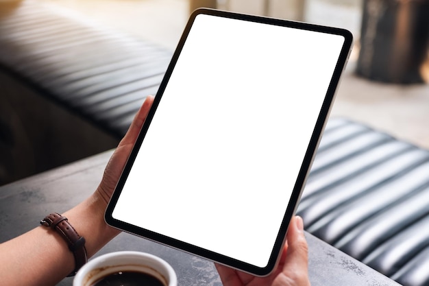 Image maquette d'une femme tenant une tablette numérique avec un écran de bureau blanc vierge dans un café