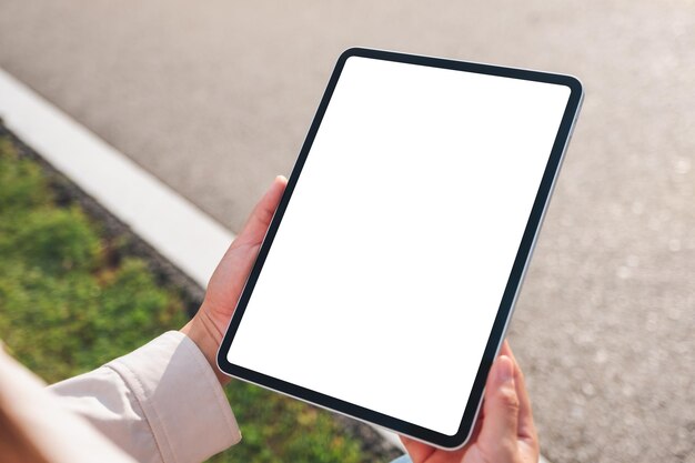 Image maquette d'une femme tenant une tablette numérique avec un écran de bureau blanc vierge à l'extérieur