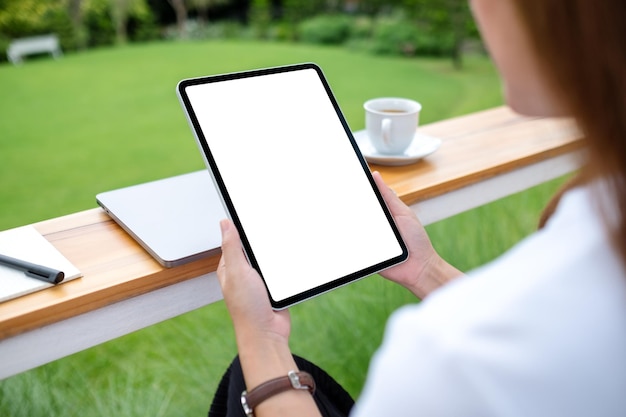 Image maquette d'une femme tenant une tablette numérique avec un écran de bureau blanc vierge à l'extérieur