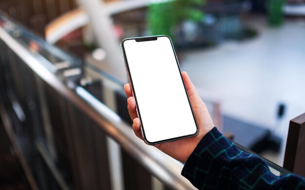 Image de maquette d'une femme tenant un téléphone portable avec un écran blanc vierge à l'intérieur