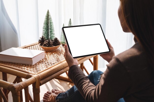 Image maquette d'une femme tenant et utilisant un Tablet PC avec un écran blanc de bureau vierge à la maison